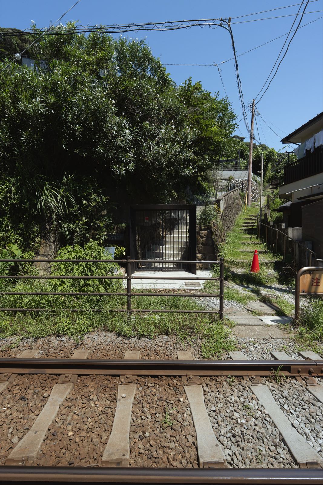江ノ電の線路越しに見た敷地入口の門と階段