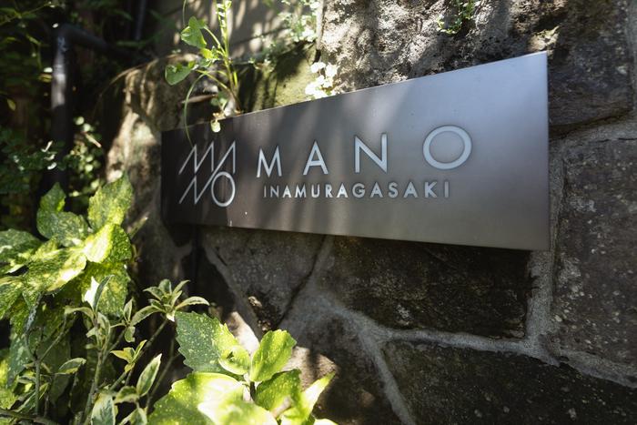 石積みの壁に取り付けられたMANO INAMURAGASAKIのサインプレート